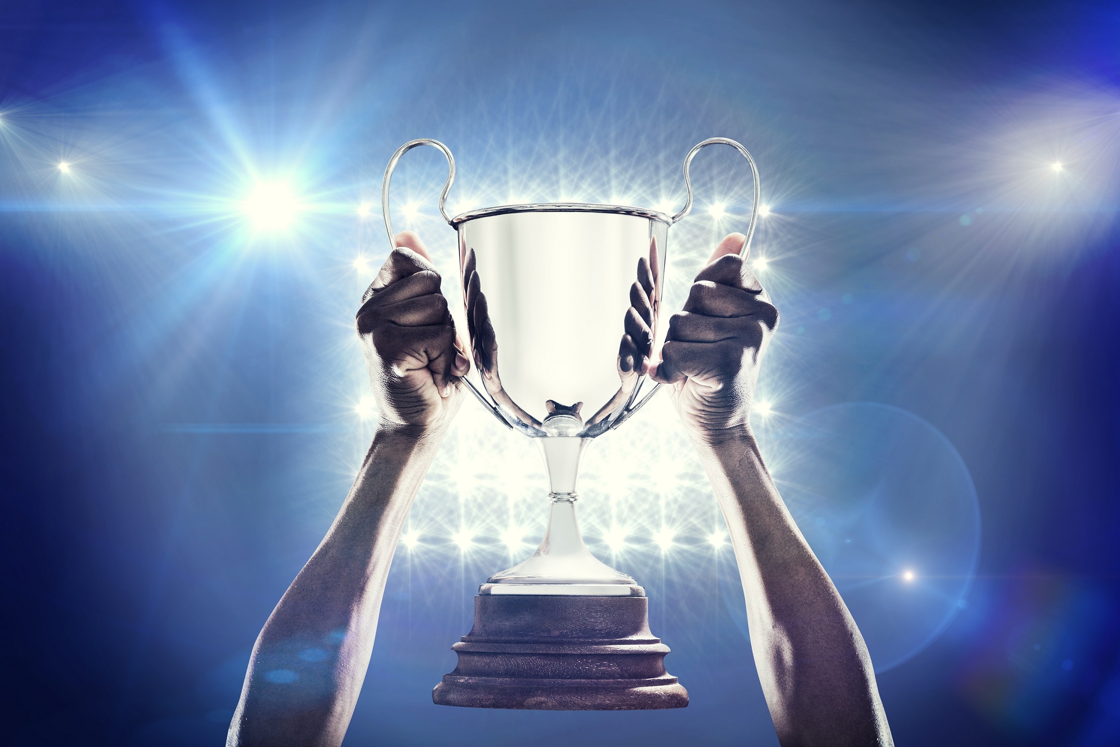 Composite image of cropped hand of athlete holding trophy
